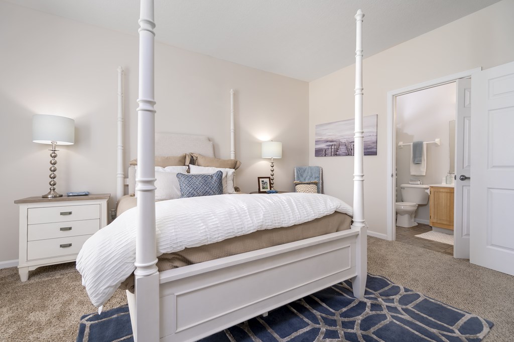 A white four poster bed with a white bedspread and pillow.