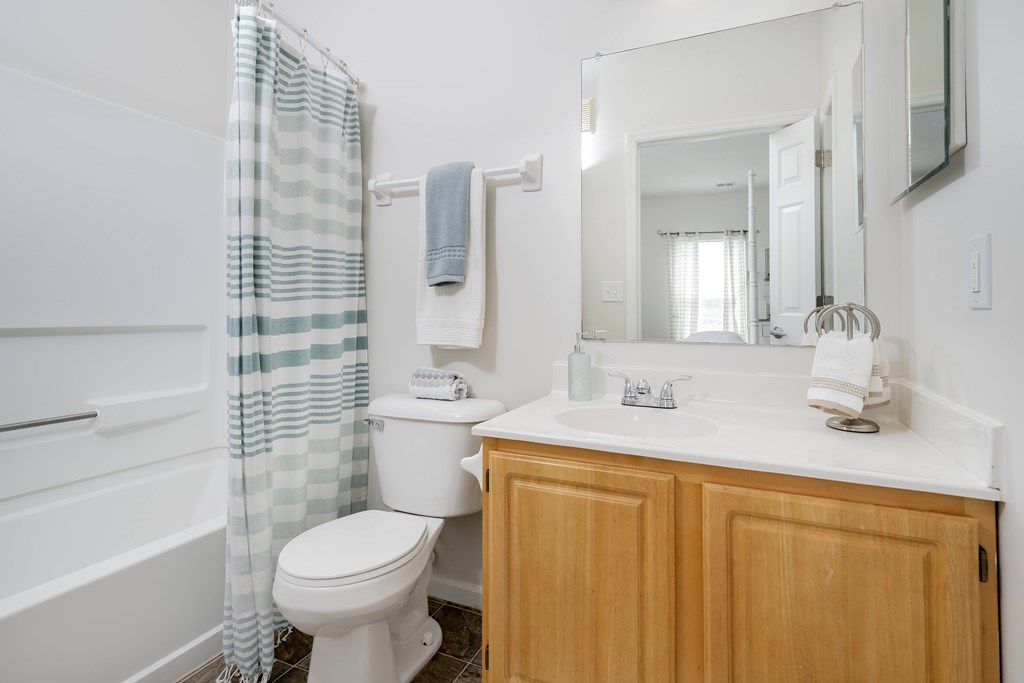 A white toilet with a blue and white striped shower curtain.