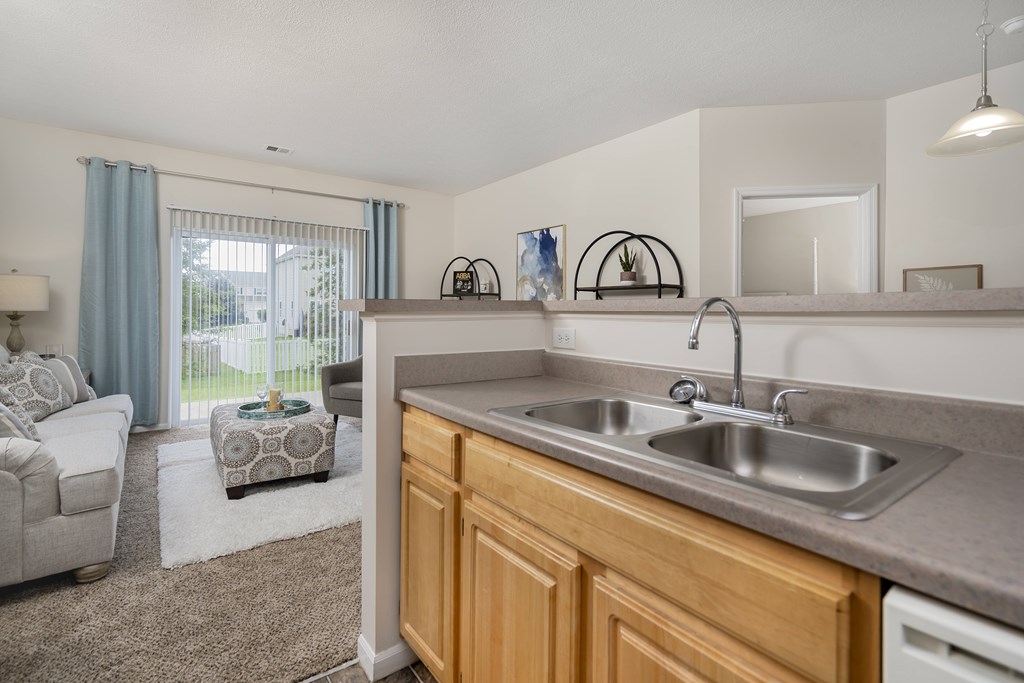 A kitchen with a sink and a window with curtains.