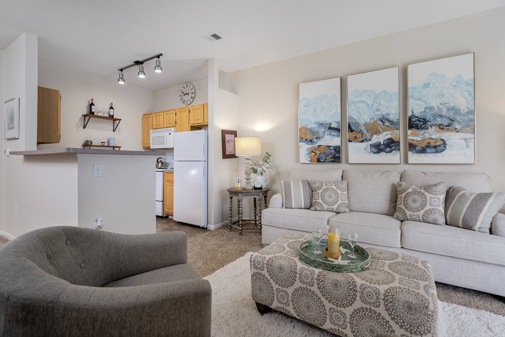 A living room with a grey armchair, a white sofa, and a coffee table with a glass top.