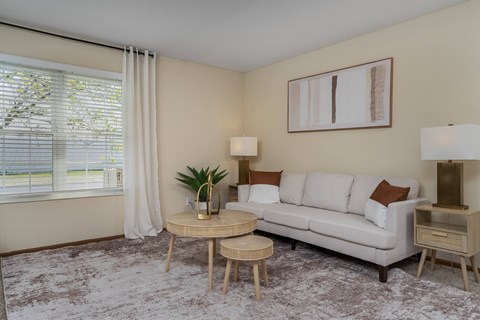 A living room with a white couch, a small table, and a painting on the wall.