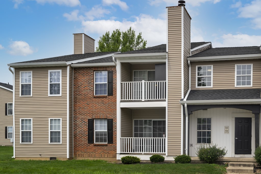 A two-story house with a balcony and a black door.