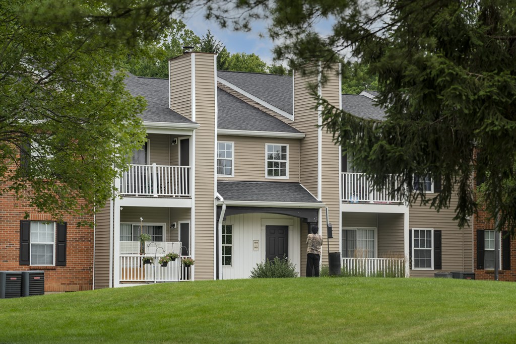 A large two story house with a balcony and a person standing in front of it.