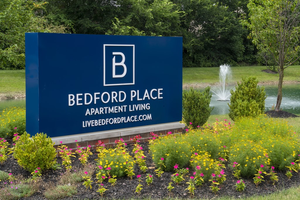 A blue sign with white lettering for Bedford Place Apartment Living.
