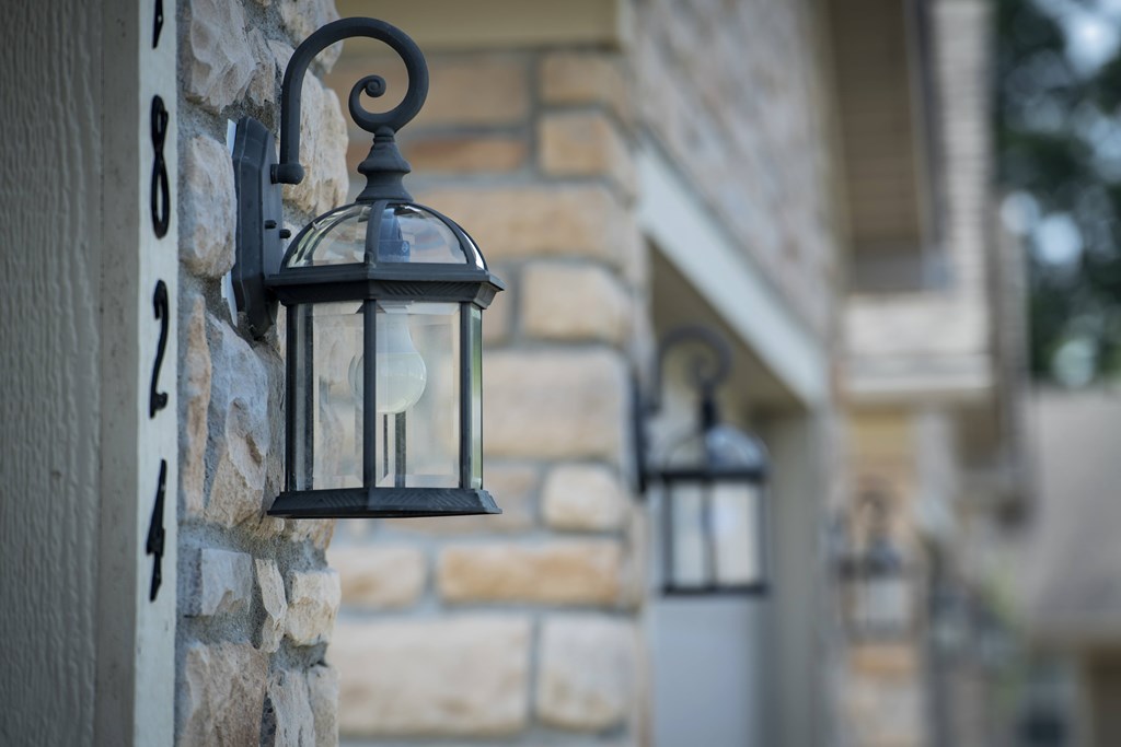 A black lantern is mounted on a stone wall.