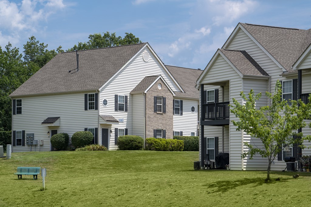 A white house with a green bench in front of it.