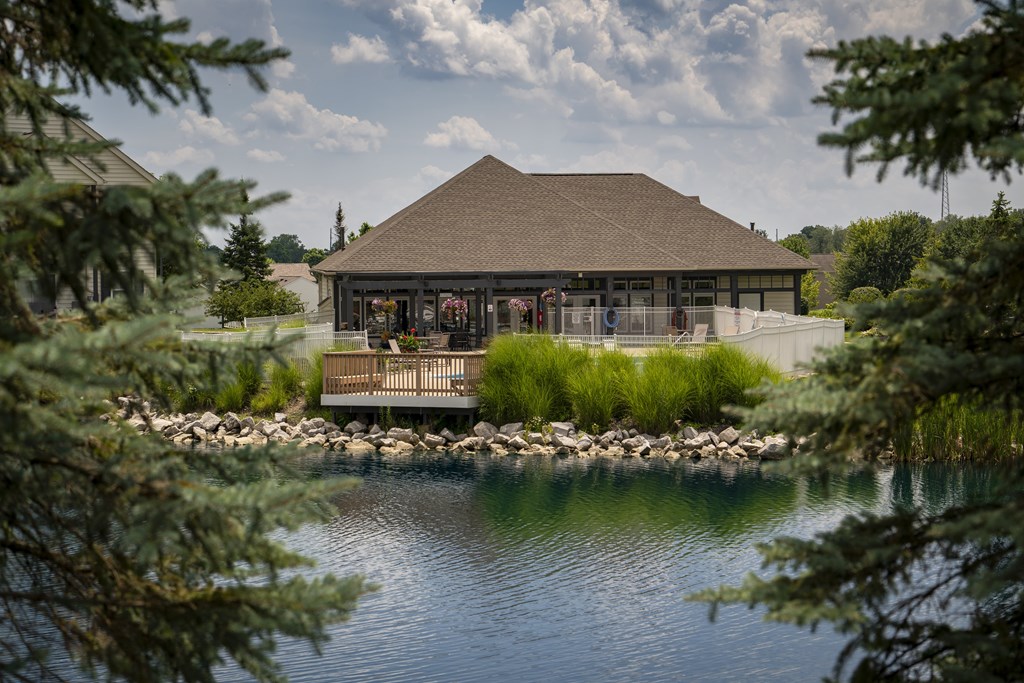 A building with a brown roof is surrounded by water and trees.