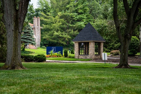 A small building with a black roof is surrounded by trees.