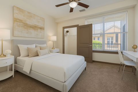 A bedroom with a large bed, a ceiling fan, and a painting on the wall.