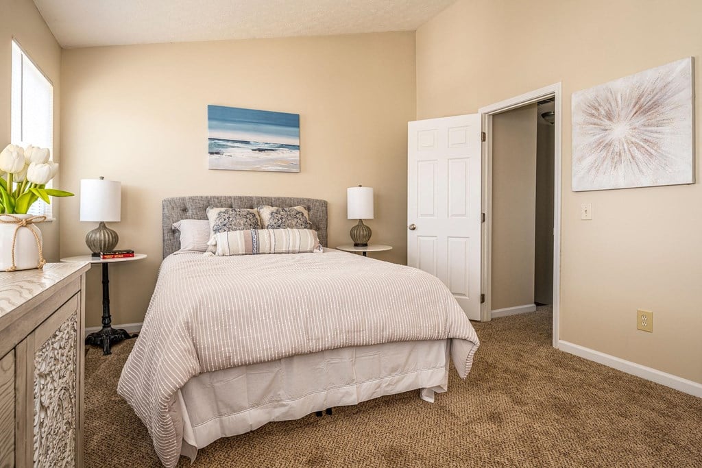 A bedroom with a large bed and a painting on the wall.