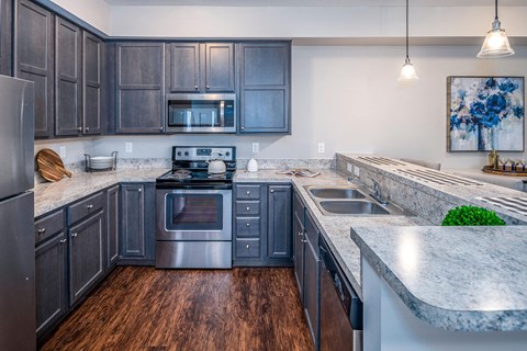A kitchen with dark wood cabinets and a granite countertop.