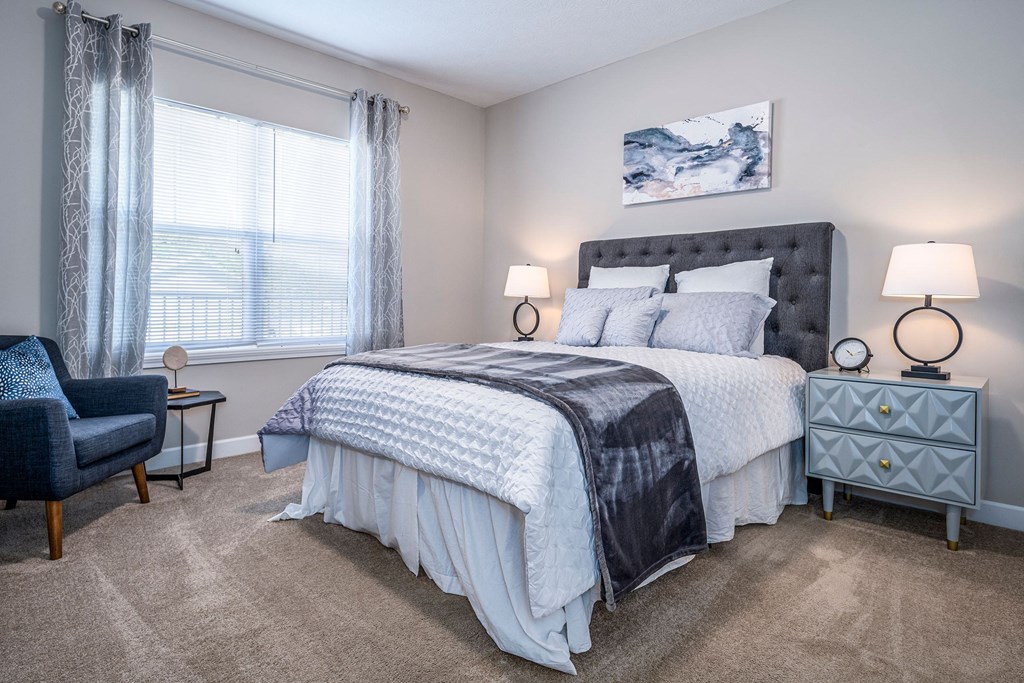 a bedroom with a bed and a chair and a window