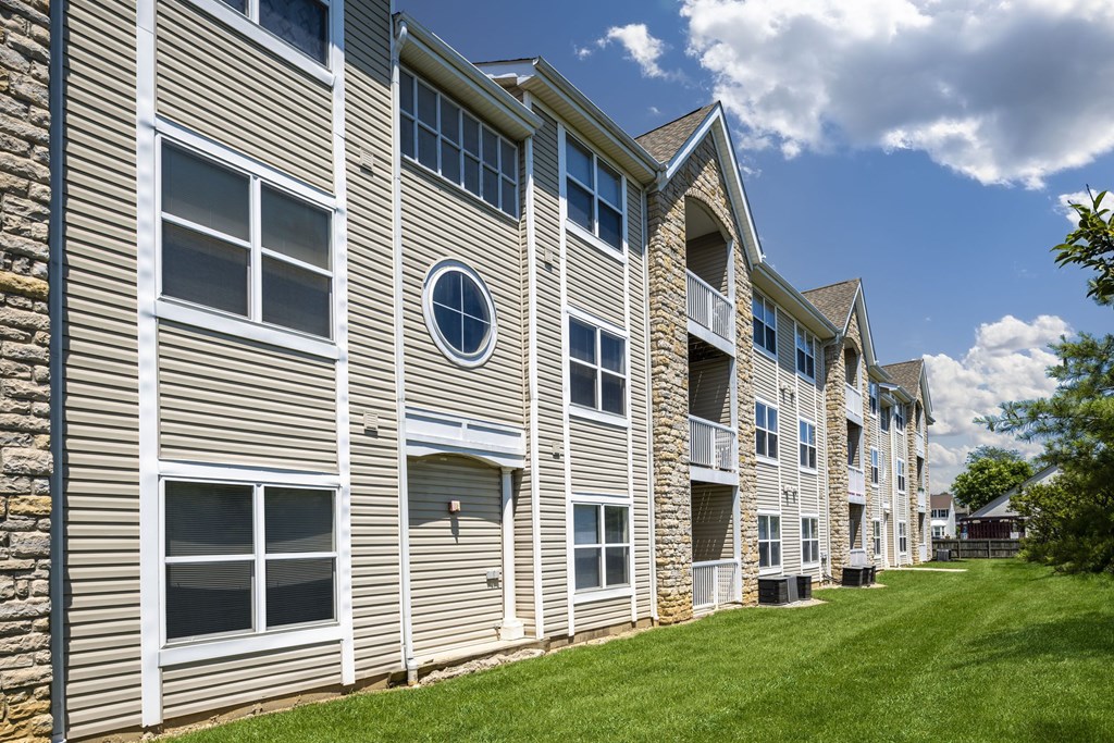 A row of apartment buildings with a green lawn in front.