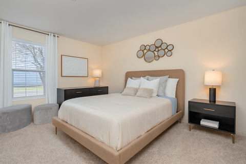 A bedroom with a large bed, two lamps, and a picture on the wall.