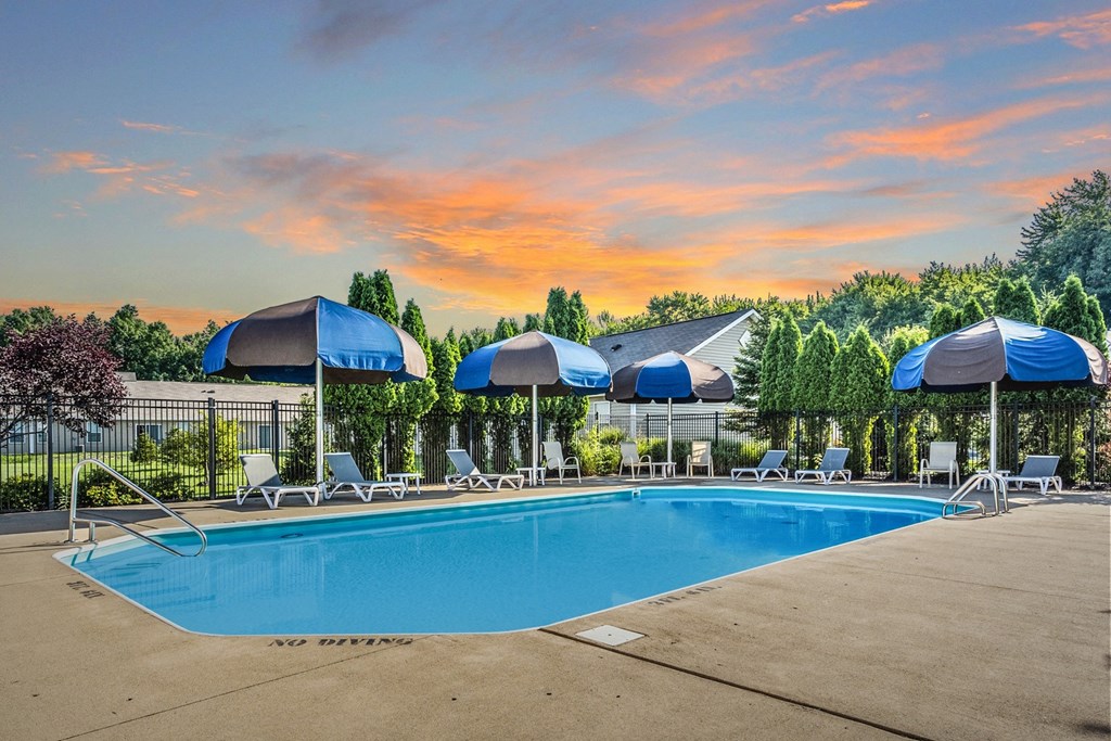a swimming pool with blue umbrellas and white lounge chairs