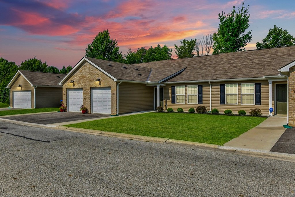 a home with a gray roof and a pink and purple sky in the background