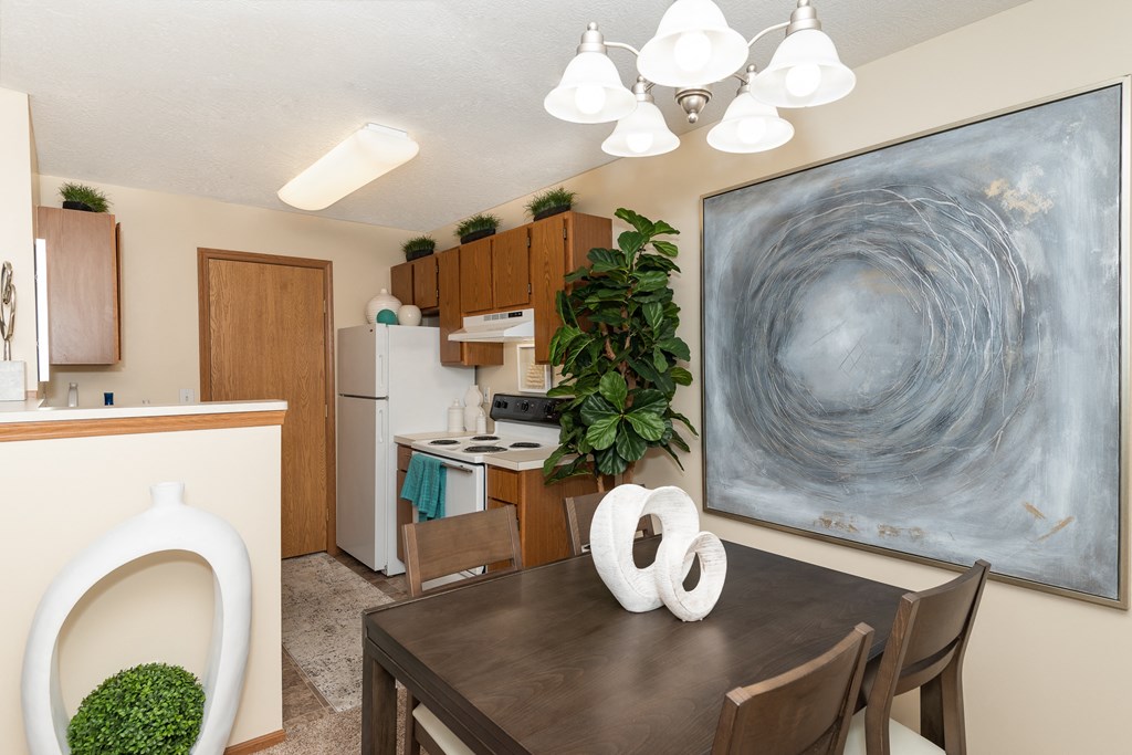 Dining area with a table and chairs, adjacent to a kitchen with modern finishes