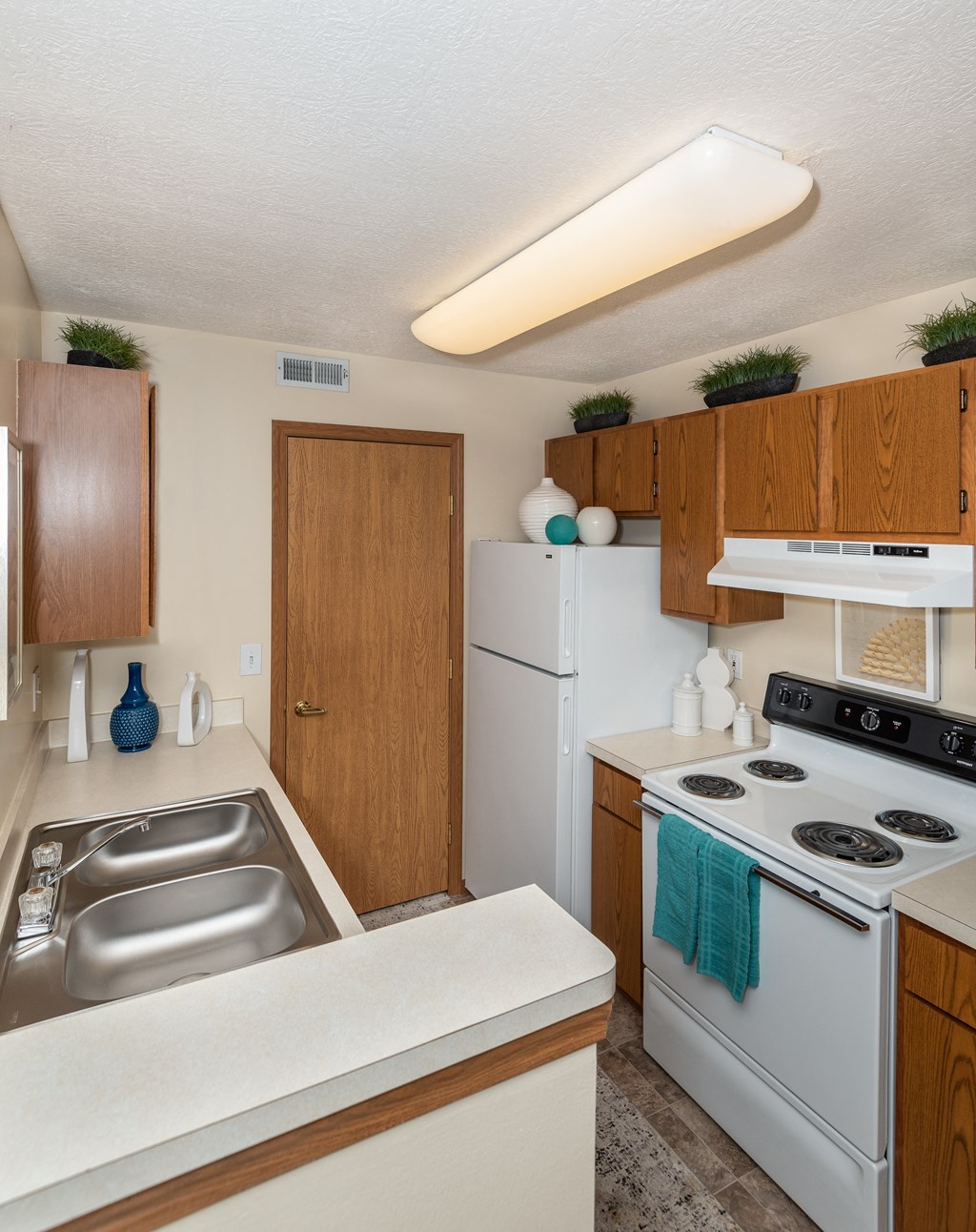 One-Bedroom Apartments in Hilliard, OH - Residences at Breckenridge - Kitchen With Wood-Style Cabinetry, Electric Stove, Refrigerator, and Dual Sinks