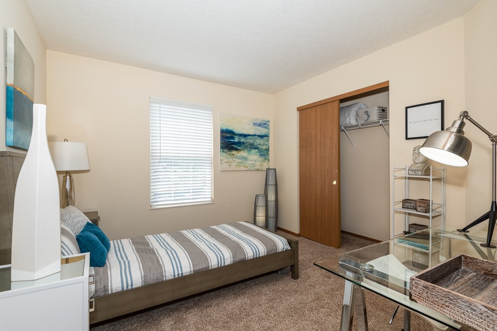 a bedroom with a bed and a glass table with a lamp