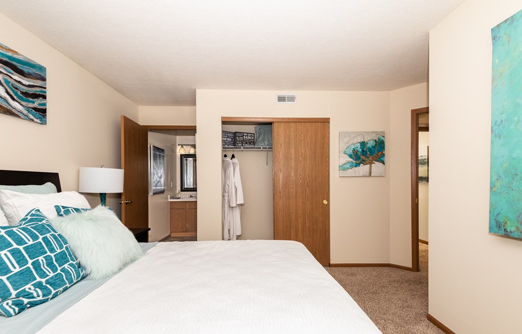 a bedroom with a large bed and a bathroom in the background