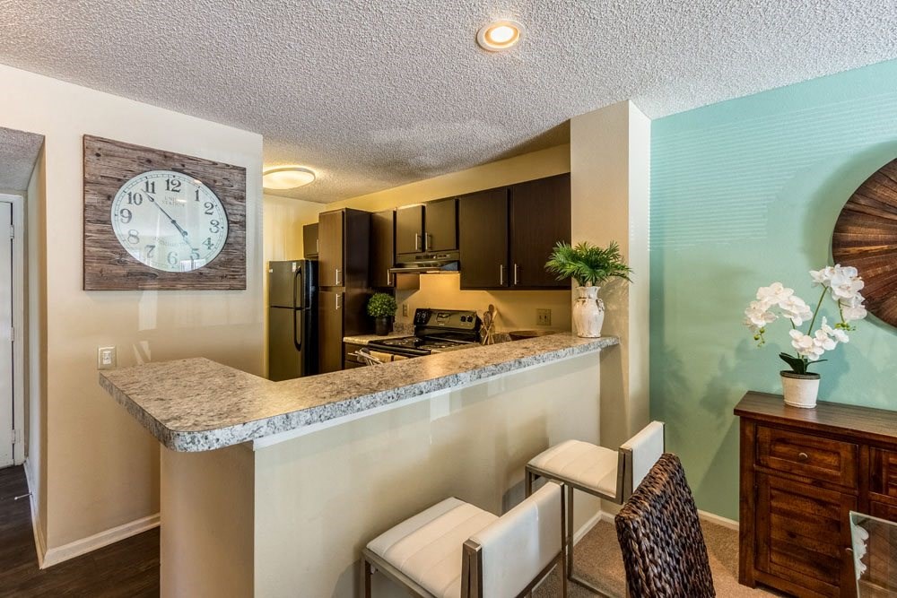 1 BR Apartments in Dublin OH - Britton Woods - Kitchen with Dark Brown Cabinets, Marble-Style Countertops, Black Appliances, and a Breakfast Bar.