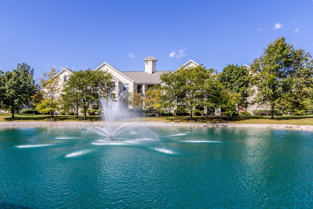 2-Bedroom Apartments in Dublin, OH - Britton Woods - Pond with a Fountain in the Middle and Beautiful Trees Surrounding