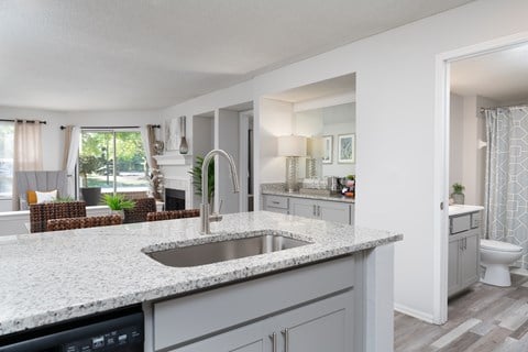 Newly renovated kitchen at Britton Woods with granite countertops, wood-style flooring, and stainless steel appliances