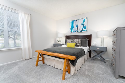Bedroom with cozy furnishings and a large window letting in natural light