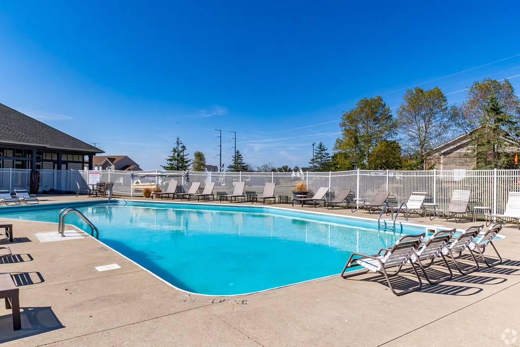 A large outdoor swimming pool surrounded by chairs and trees.