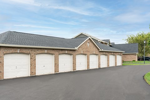 A row of white garage doors are on the side of a building.