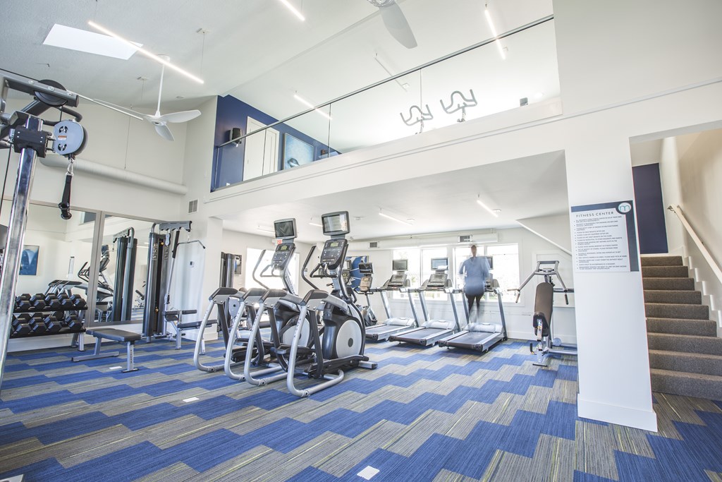 A gym with a variety of equipment including treadmills, weights, and exercise machines.