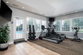 A home gym with a variety of exercise equipment including a treadmill, stationary bike, and a bench press.