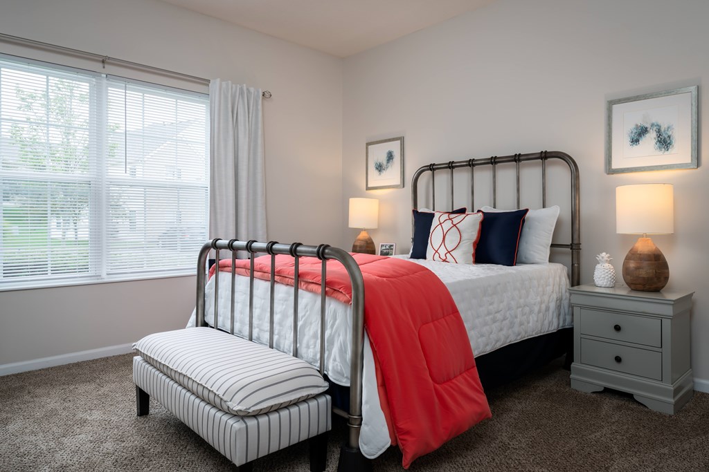 A bedroom with a large bed and a smaller bed with a red blanket.