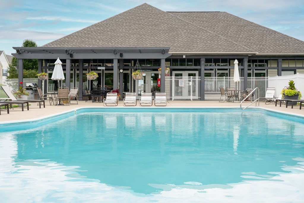 a swimming pool with chairs and umbrellas in front of a building