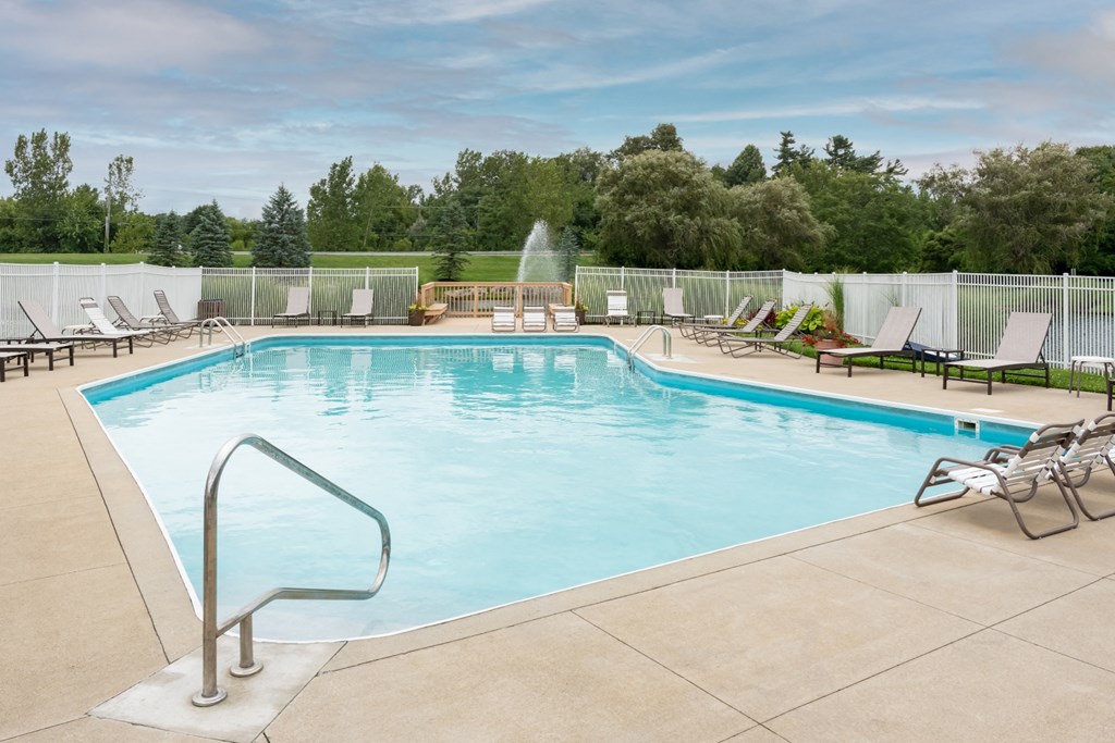 a swimming pool with chaise lounge chairs and trees in the background