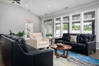 A living room with a black couch, a white chair, and a coffee table.