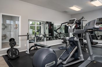 A gym with a variety of equipment including a treadmill, weights and a bench.