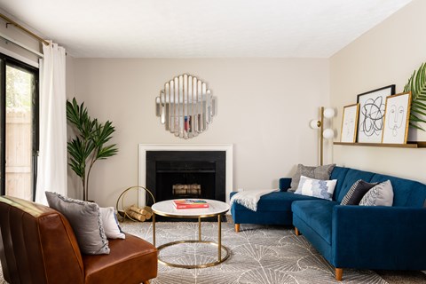 A living room with a fireplace, a blue couch, and a plant.