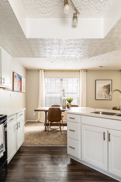 Fairway Lakes kitchen with white cabinets and hardwood-style flooring, situated next to a dining room table.