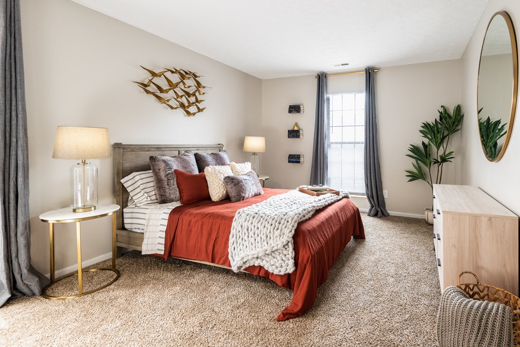 One BR Apartments in Westerville, OH - Fairway Lakes - Spacious Bedroom with Bed, Dresser, Nightstands, Lamps, Carpet Flooring, and a Window.