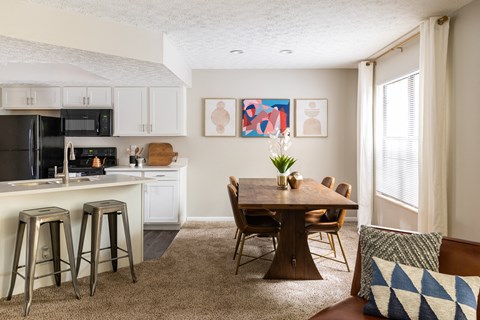 Fairway Lakes dining room featuring a dining room table, carpeted flooring, and modern decor, situated next to a kitchen.