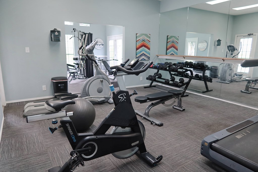 Fully equipped fitness center at The Boulevard in Florence, KY with free weights, bench press, and mirrored walls