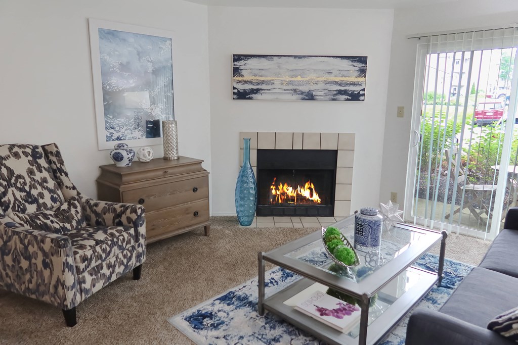 Pet-Friendly Apartments in Florence, KY - Boulevard - Furnished Living Room with Fireplace, Carpet Flooring, High Ceilings, and a Sliding Glass Door to a Private Patio