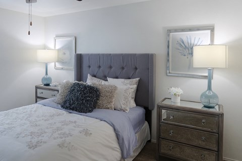Stylish bedroom with plush carpet, ceiling fan, and vaulted ceiling in a one-bedroom apartment at The Boulevard