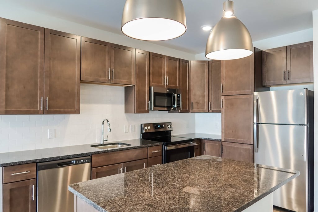 Madamore Apartments - Large Chef-Ready Kitchens with Dark Cabinets, Pantries, and Stainless Steel Appliances A kitchen with dark cabinets, stainless steel appliances, and an island.