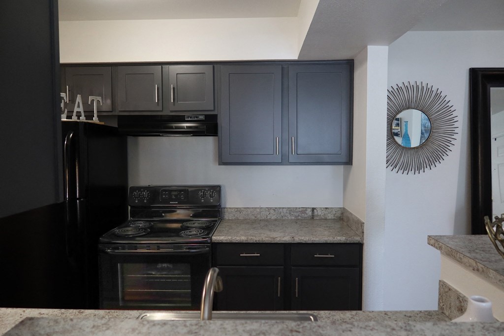 Kitchen with granite countertops and black appliances in a modern apartment setting
