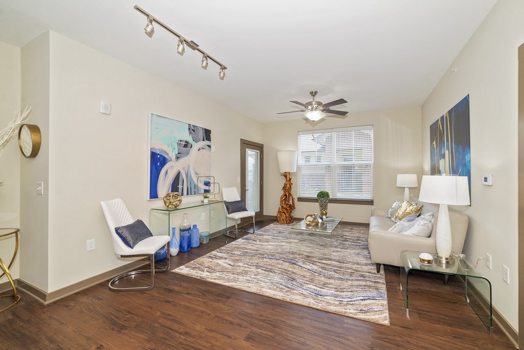 Studio Apartments in Miamisburg, OH - Austin Park - Living Room with Couch, Coffee Table. End Table, Ceiling Fan, Area Rug, Wood-Style Flooring, Exterior Door, and Window.