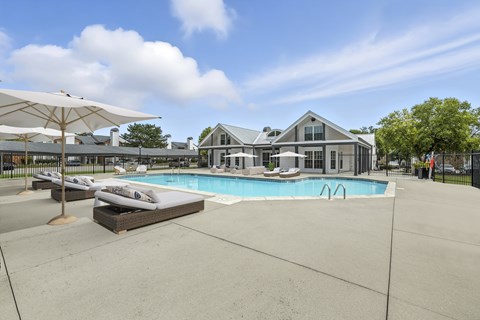 A large outdoor swimming pool with sun loungers and umbrellas.