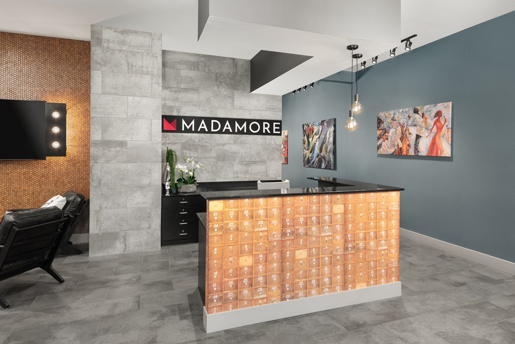 Lobby at Madamore Apartments with a desk, light fixtures, and stylish decor.