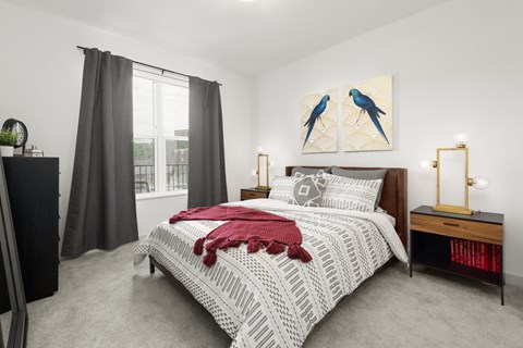 A furnished bedroom at Madamore with carpeted flooring and a window for natural light.